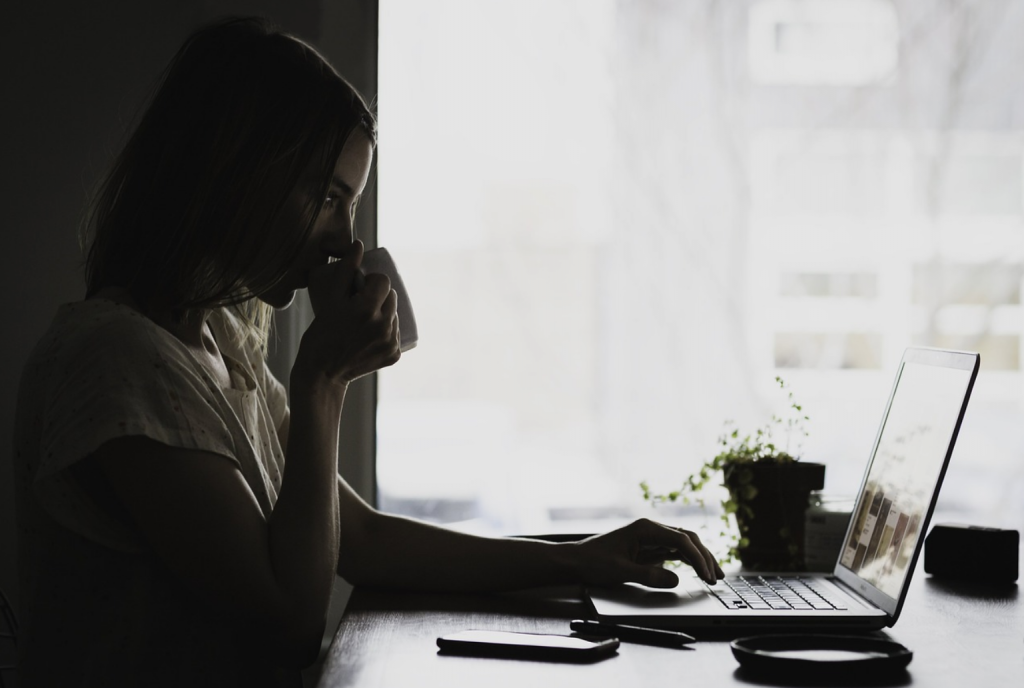 Image d'une jeune femme faisant des achats sur un site de commerce électronique à l'aide d'un ordinateur portable et d'un téléphone portable. Le commerce électronique a changé le comportement des clients à la fois en ligne et hors ligne.