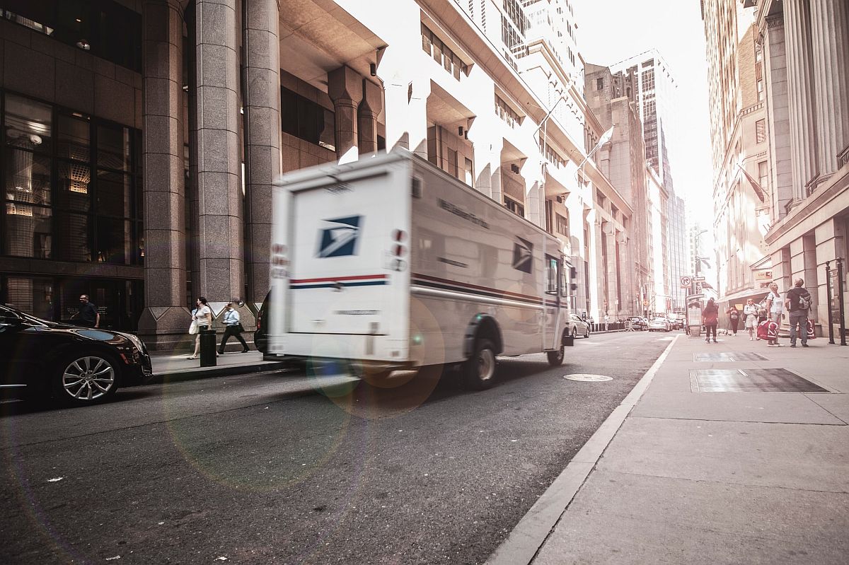 USPS teslimat kamyonu yoğun bir şehirde hızla geçiyor; e-Ticaret konsepti için karbon dengeleme