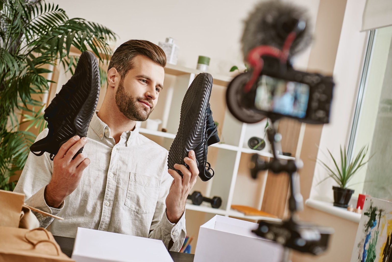 joven sostiene un par de zapatos para una cámara; concepto de comercio electrónico de transmisión en vivo