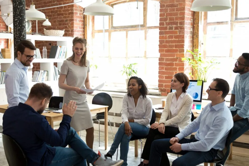 Fünf Büroangestellte sitzen beiläufig in einer Besprechung. Mitarbeiterläden sorgen dafür, dass Mitarbeiter wie diese engagiert und glücklich sind.