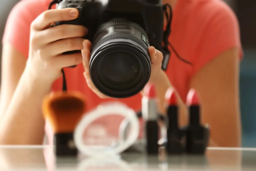 Una fotocamera digitale scatta una foto di prodotti con rossetto rosso