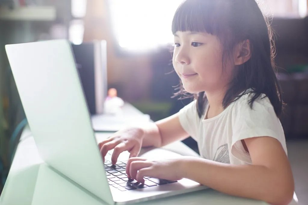 Una foto de primer plano de una niña que usa una computadora portátil para jugar juegos de computadora