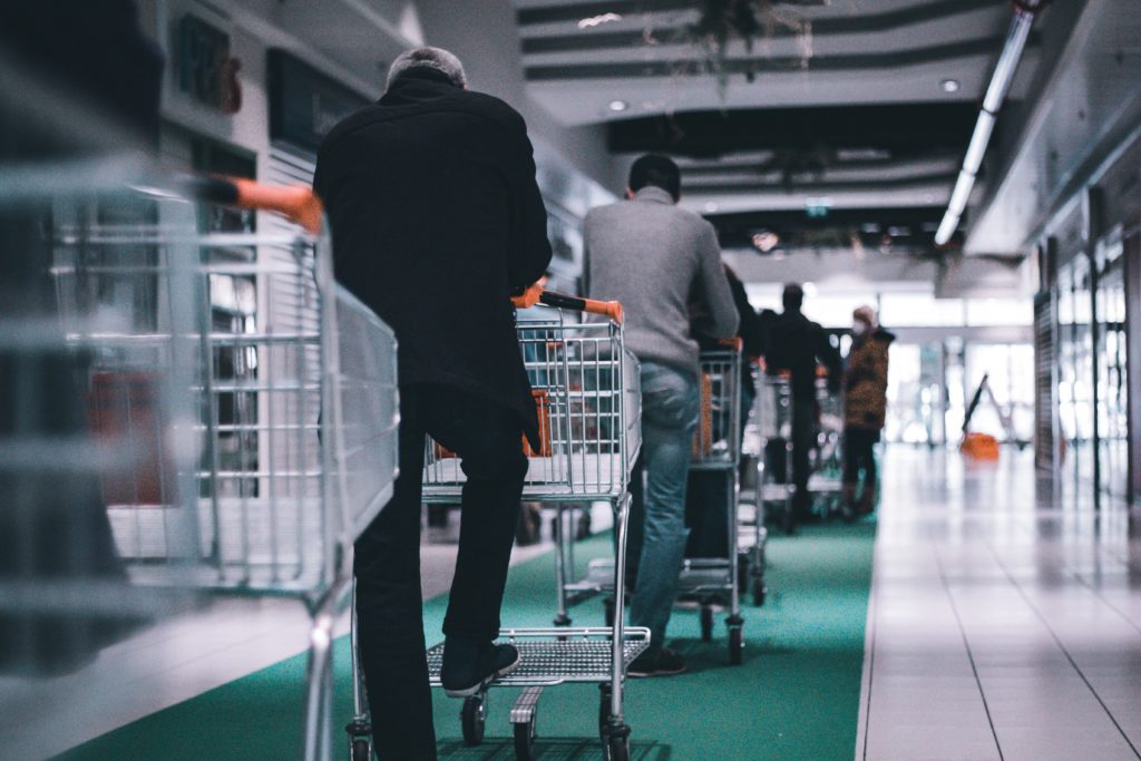 Gli acquirenti con i carrelli della spesa in fila in attesa di fare il check-out in un negozio.