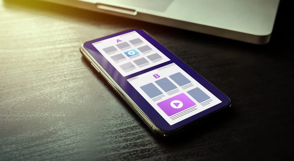 telefon komórkowy z dwiema ilustrowanymi opcjami układu strony internetowej, aby zilustrować testy A/B