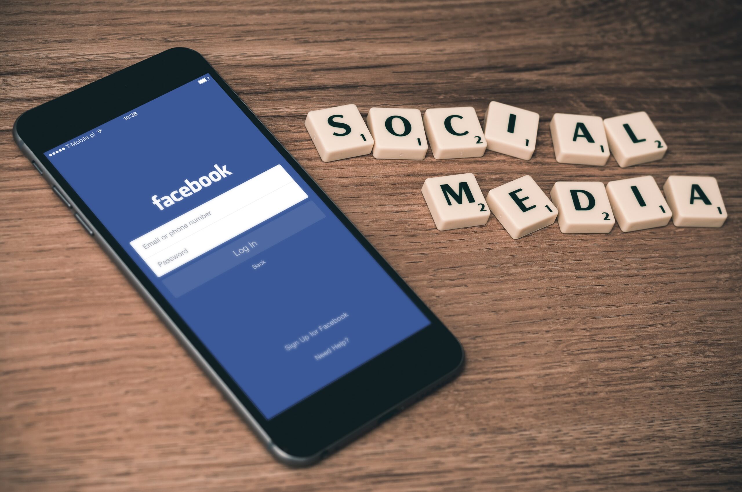 smartphone con l'app Facebook aperta e i social media scritti con parole di scarabeo