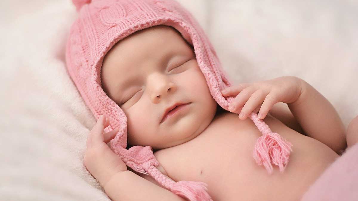 petite fille nouveau-née portant un chapeau rose.