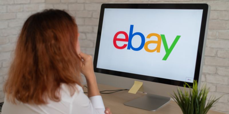 Mulher olhando para o logotipo do Ebay em um monitor de computador