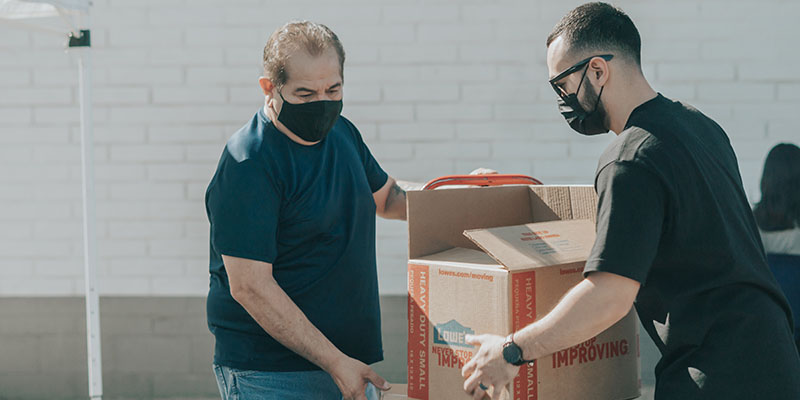 Dois homens vestidos com caixas de embalagem de camisetas pretas