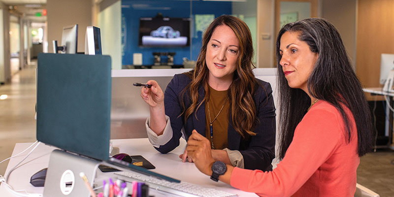 Duas mulheres de negócios falando sobre vendas no escritório na mesa com laptop