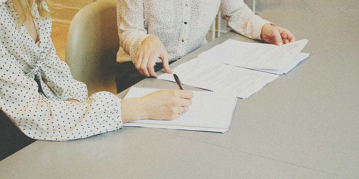 Deux personnes signant un ensemble de formulaires papier