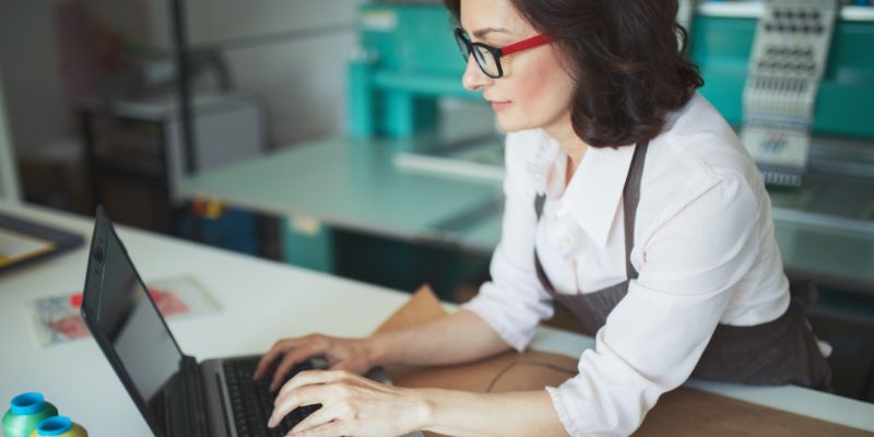 Femme s'appuyant sur un comptoir à l'aide d'un ordinateur portable