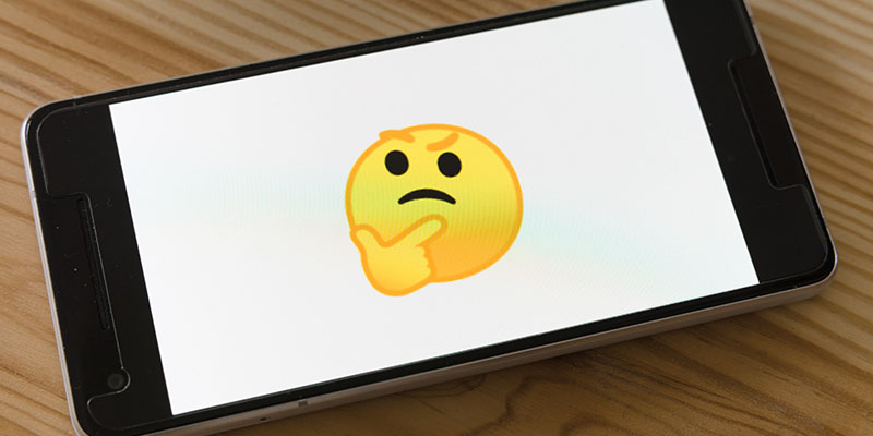 Ein denkendes gelbes Emoji auf einem Handy