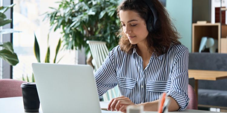 Mujer escribiendo en un trabajo de servicio al cliente con auriculares