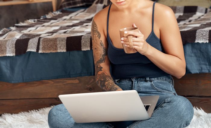 donna sul suo computer con in mano una tazza di caffè