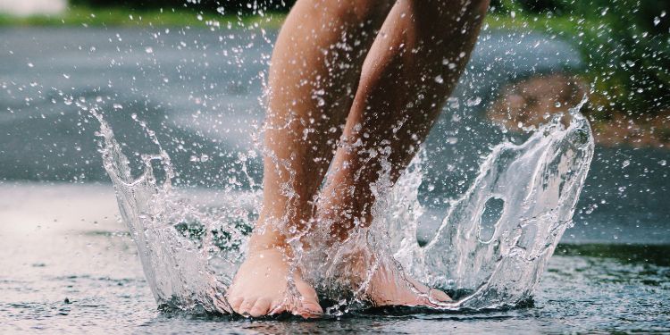 les pieds pataugeant dans une flaque d'eau