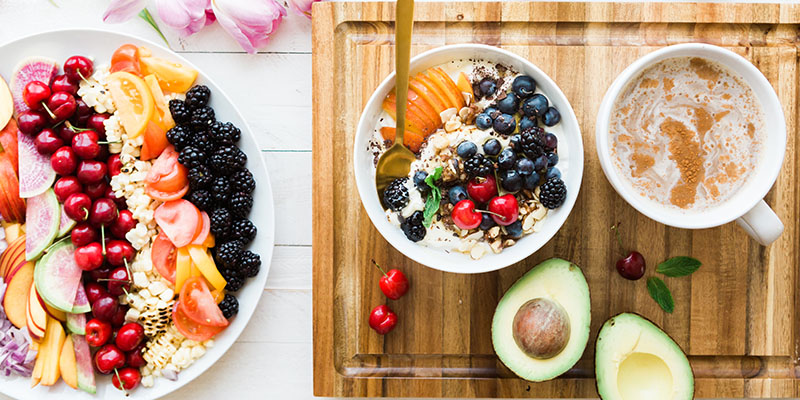 Um prato e duas tigelas cheias de bagas e frutas