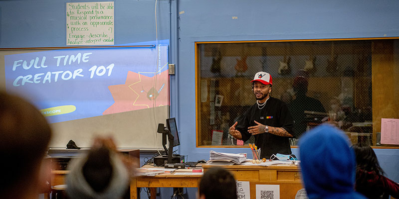 Um homem dando uma palestra sobre o "Criador 101" para alunos em uma classe