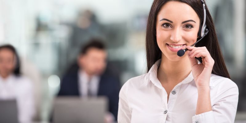 representante de call center usando fone de ouvido com outros representantes sentados ao fundo