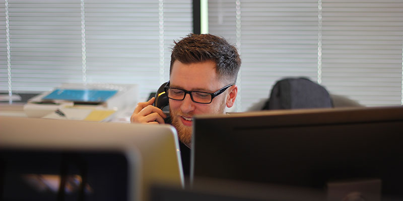 Um homem atendendo um telefone em sua mesa de escritório