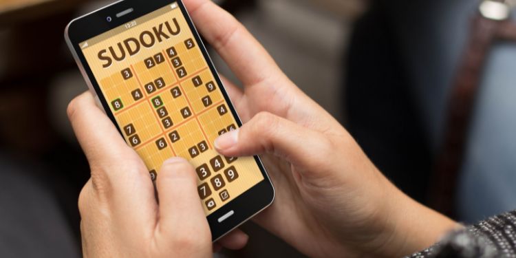 elinde sudoku uygulaması açık olan bir akıllı telefon tutan kişi