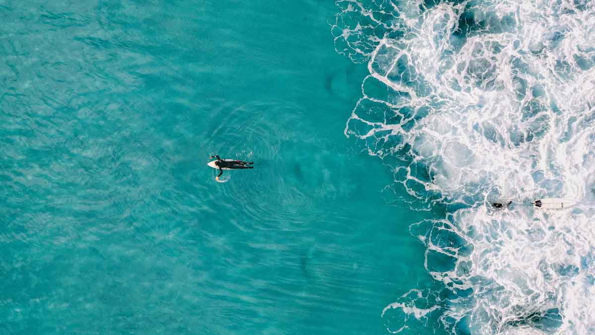 océano azul turquesa con surfista nadando al mar.