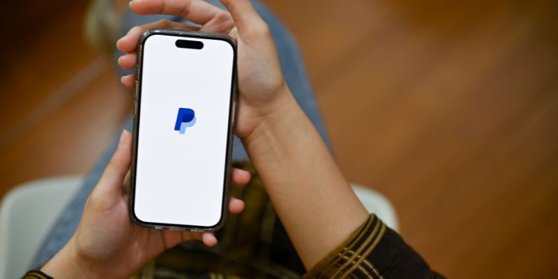 mãos segurando um smartphone com logotipo do paypal