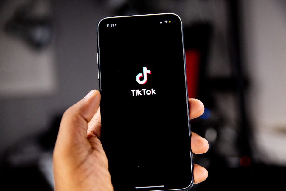 Mão segurando o telefone com o logotipo do TikTok na tela preta