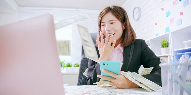 Donna che guarda lo schermo di un computer circondato da banconote da un dollaro