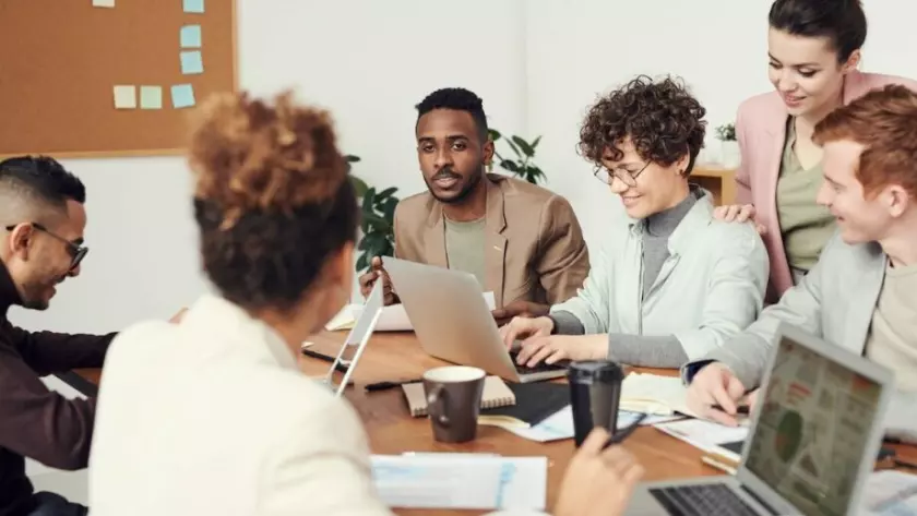 Un grupo de personas sentadas alrededor de una mesa con ordenadores portátiles.