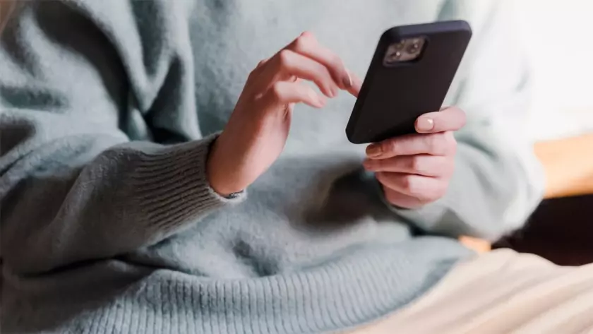 Una mujer sosteniendo un teléfono mientras estaba sentada en un sofá.