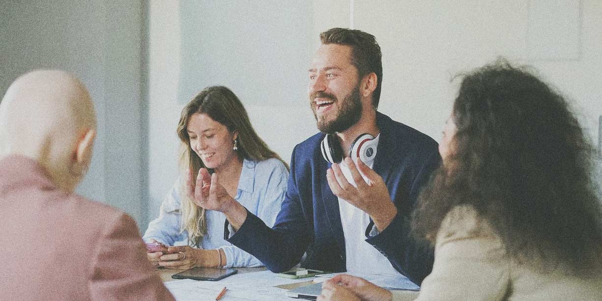 Hombre de chaqueta azul hablando con un grupo de compañeros de trabajo