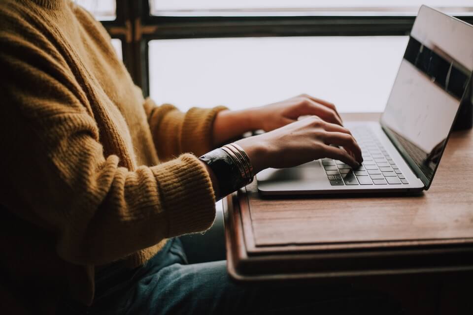 Una persona escribiendo un blog en una computadora portátil.