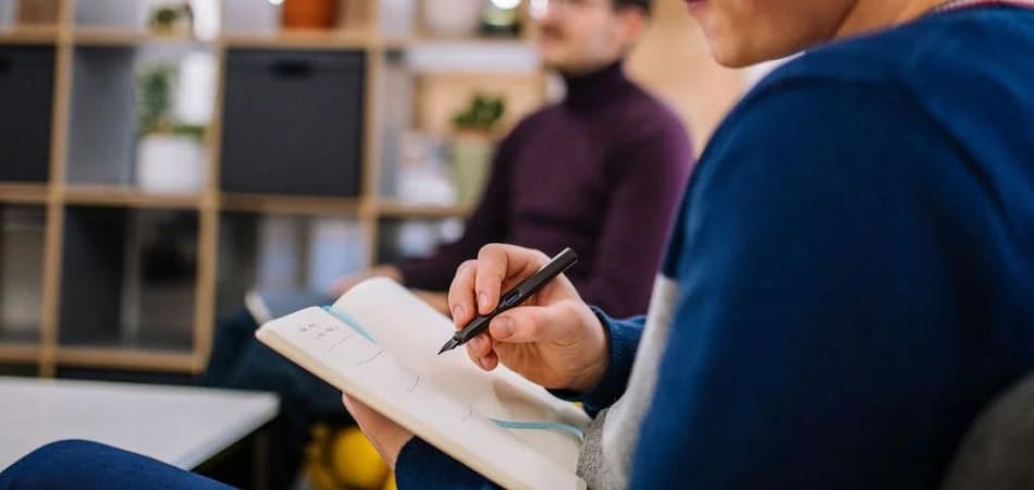 Um funcionário do sexo masculino da Gripped estava sentado em um espaço de descanso, escrevendo em um caderno.